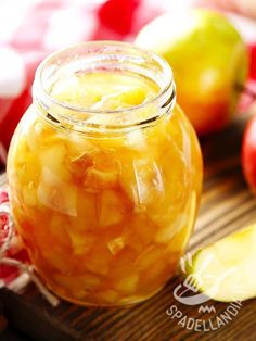 an apple cider is sitting on a cutting board with apples in the back ground