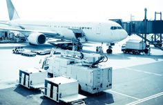 an airplane is parked on the tarmac with other vehicles around it and luggage being unloaded