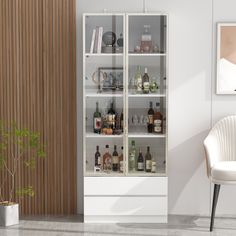 a white chair sitting in front of a tall glass cabinet filled with bottles and liquor