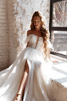 a woman in a white dress sitting on a window sill next to a brick wall