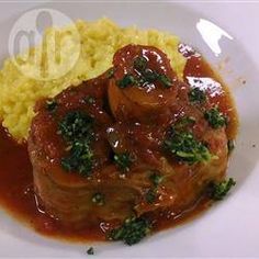 a white plate topped with meat and gravy covered in sauce on top of yellow rice