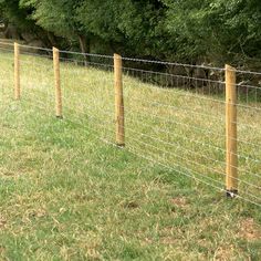 a wire fence with wooden posts in the grass