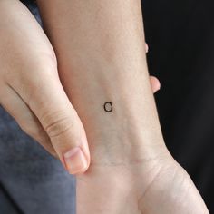 a woman's wrist with a small tattoo on the left side of her arm