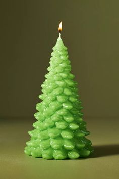 a small green christmas tree with a lit candle in the middle on a brown background