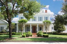 a white house with trees and bushes around it