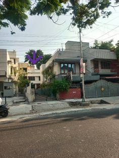 a motorcycle is parked on the street in front of some houses with purple balloons attached to them