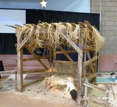 a nativity scene made out of hay and straw with a star hanging from the roof