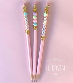 three pink pencils with beads on them sitting next to each other in front of a purple background