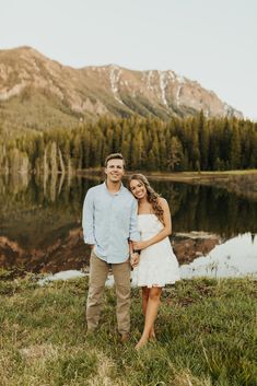 a couple standing next to each other in front of a lake