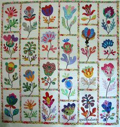 a quilted wall hanging with colorful flowers on it