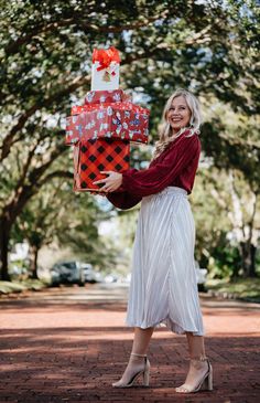 a woman in a white dress is holding a gift box and smiling at the camera