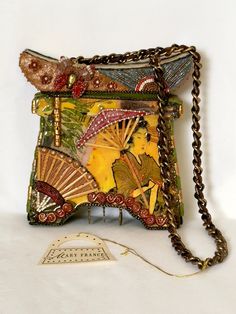 a small purse with a chain hanging from it's side and an image of a woman holding a fan on the front