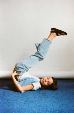 a woman laying on the floor with her feet up in the air while wearing jeans