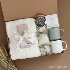 an open box with some items in it and a white ribbon around the top, sitting on a table next to a potted plant