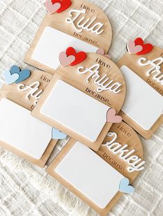 four personalized wooden plaques with hearts and name tags on the front, two are blank