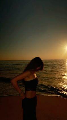 a woman standing on top of a beach next to the ocean