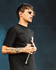 a man in black shirt and sunglasses holding a microphone