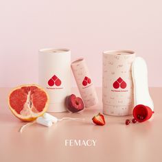 the fruit is next to two cups with strawberries on them and one grapefruit