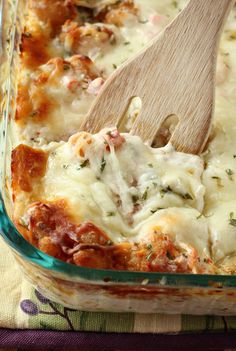 a casserole dish with meat and cheese being stirred with a wooden spatula