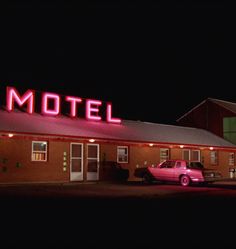 an old motel lit up at night with the word motel on it's roof