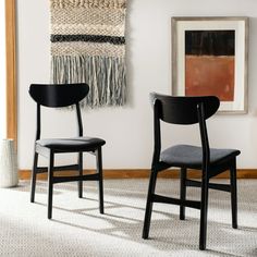 two black chairs sitting next to each other in front of a painting on the wall