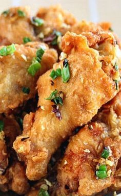 some fried food on a white plate with green onions and seasoning sprinkles