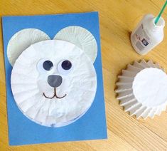 a paper plate with a bear face on it next to cupcakes and a bottle of milk