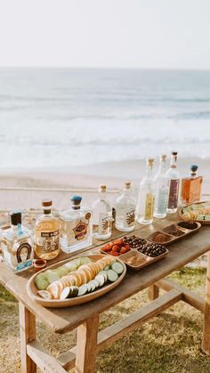 an outdoor picnic table with food and drinks on it near the water's edge