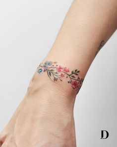 a woman's hand with a flower tattoo on her left wrist and the other arm