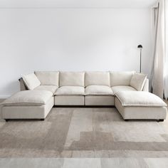 a living room with a large sectional couch and rugs on the floor in front of a window