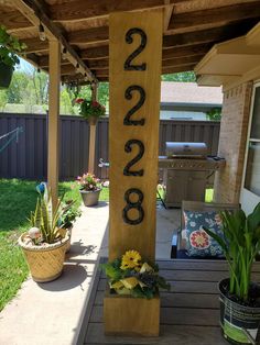 a wooden sign with numbers on it in front of a house and some potted plants