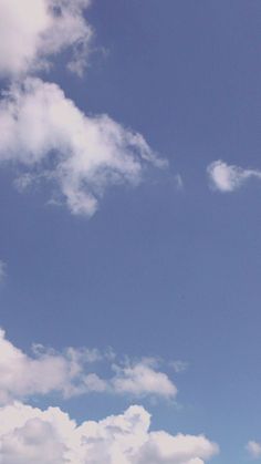 a group of people standing on top of a lush green field under a blue sky