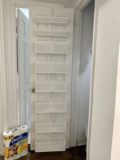 the door is open and there are white shelves on the wall in front of it