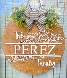 a wooden sign that says the perfez family hanging on a door with flowers