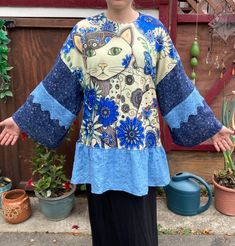 "UPCYCLED with multiple fabrics. OOAK.  The main blouse is stretchy and feels like cotton or cotton blend. The sleeves and ruffle are cotton. All prewashed. Best fits large or XL, but SEE MEASUREMENTS BELOW.   Sleeve length from center back 28\" Bust 46\" Hips 46\" at top of ruffle Length from center back 30\" Model is size Medium My home is smoke free. Clothing is measured while laying flat and unstretched. I highly recommend taking the time to measure something that fits you well for comparison. Remember that you need breathing room that is not included in the measurements.  Any flaws are described above.  All items are sent with delivery confirmation and insurance in the U.S., or First Class International. 30% of the profits for 2023 will go to the following charities : 20% Mercy for An Blue Stretch Tops With Patchwork, Blue Stretch Patchwork Tops, Lagenlook Patchwork Top With Relaxed Fit, Stretch Cotton Crew Neck Blouse, Lagenlook Relaxed Fit Patchwork Tops, Blue Lagenlook Tops With Relaxed Fit, Blue Patchwork Relaxed Fit Blouse, Blue Relaxed Fit Patchwork Blouse, Relaxed Fit Blue Patchwork Blouse