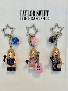 three lego key chains with the words taylor swift, the eras tour on them and a guitar