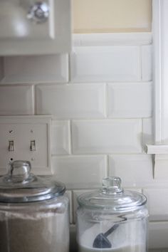 two glass jars sitting next to each other on a counter