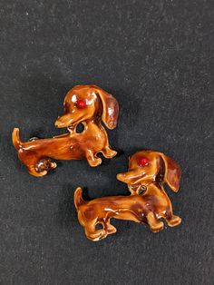 two brown dog brooches sitting on top of a black surface