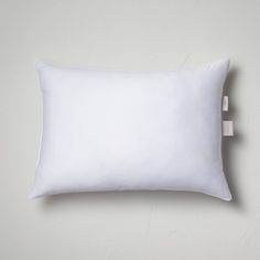 a white pillow sitting on top of a bed next to an electrical outlet in the wall