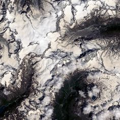 an aerial view of snow covered mountains and clouds