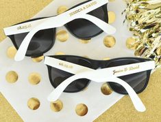 two black and white sunglasses with gold confetti on them next to each other