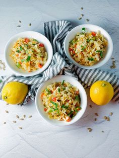 three white bowls filled with food next to two lemons