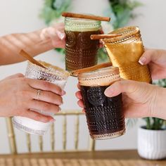 three people are holding up their cups to each other with cinnamon sticks sticking out of them