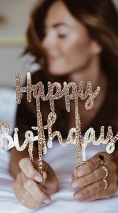 a woman holding up a happy birthday cake topper