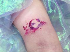 a woman's leg with a tattoo on it that has butterflies flying around the moon