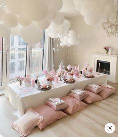 a long table is set with pink pillows and white balloons in the shape of clouds