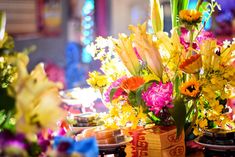 flowers and candles are arranged in vases on a table with other items around it