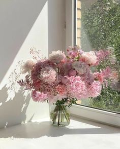 a vase filled with pink flowers next to a window