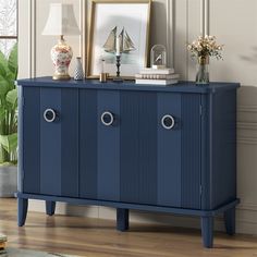 a blue cabinet with two doors and three drawers in front of a window, next to a lamp