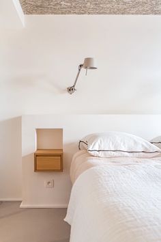 a bedroom with a bed, night stand and lamp on the wall next to it